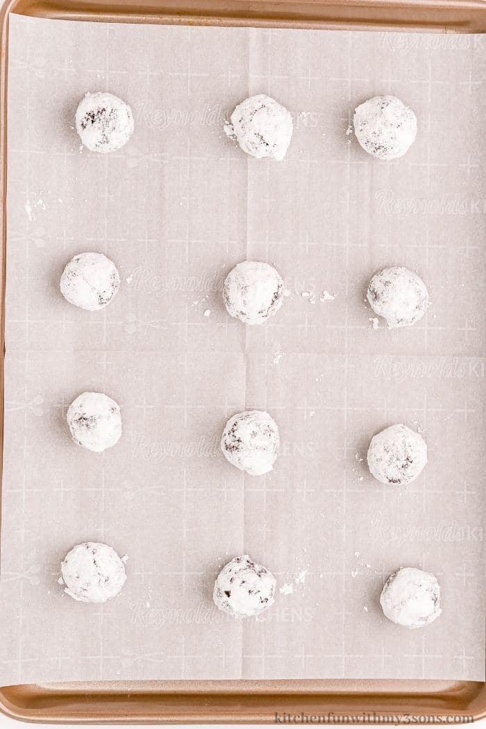 Balls of cookie dough on a sheet pan.