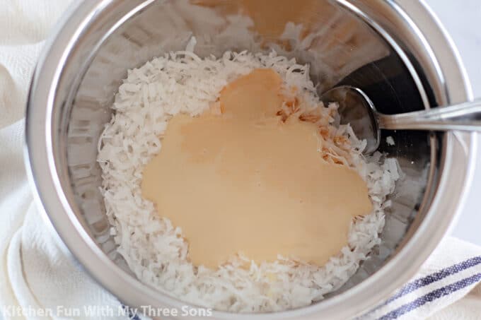 stirring together coconut and sweetened condensed milk in a bowl.