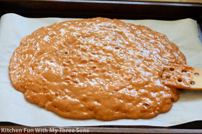 spreading the hot peanut brittle out onto a cookie sheet.