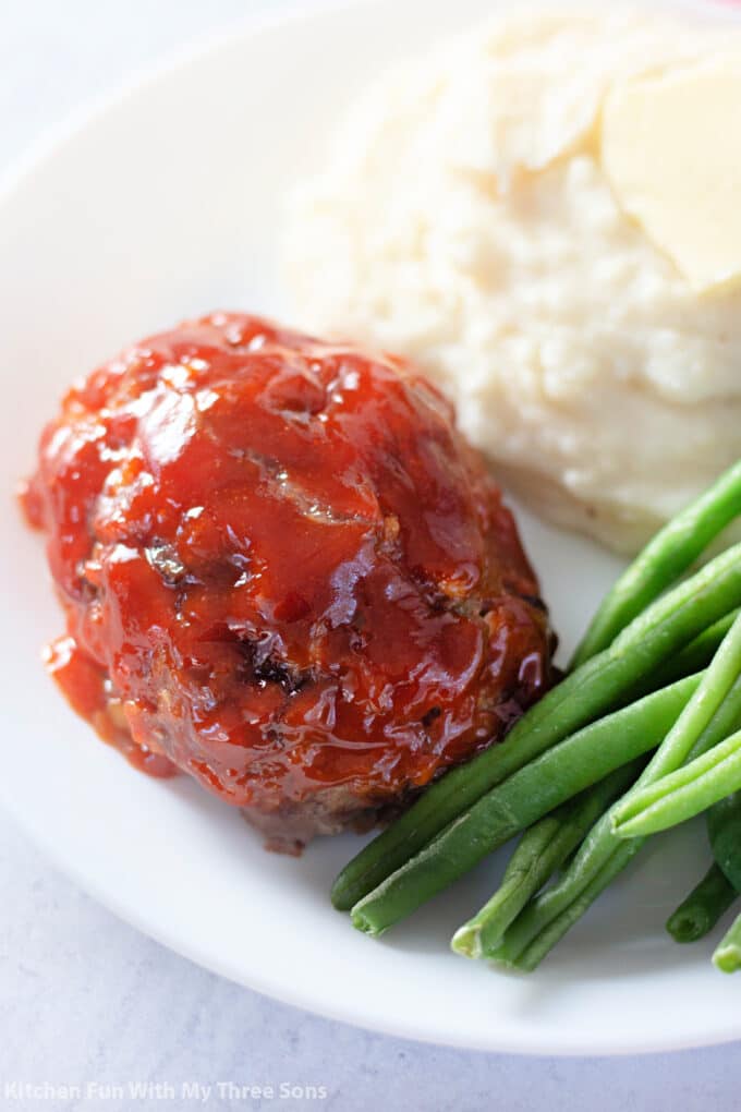 Mini Meatloaf on a plate with mashed potatoes and green beans.