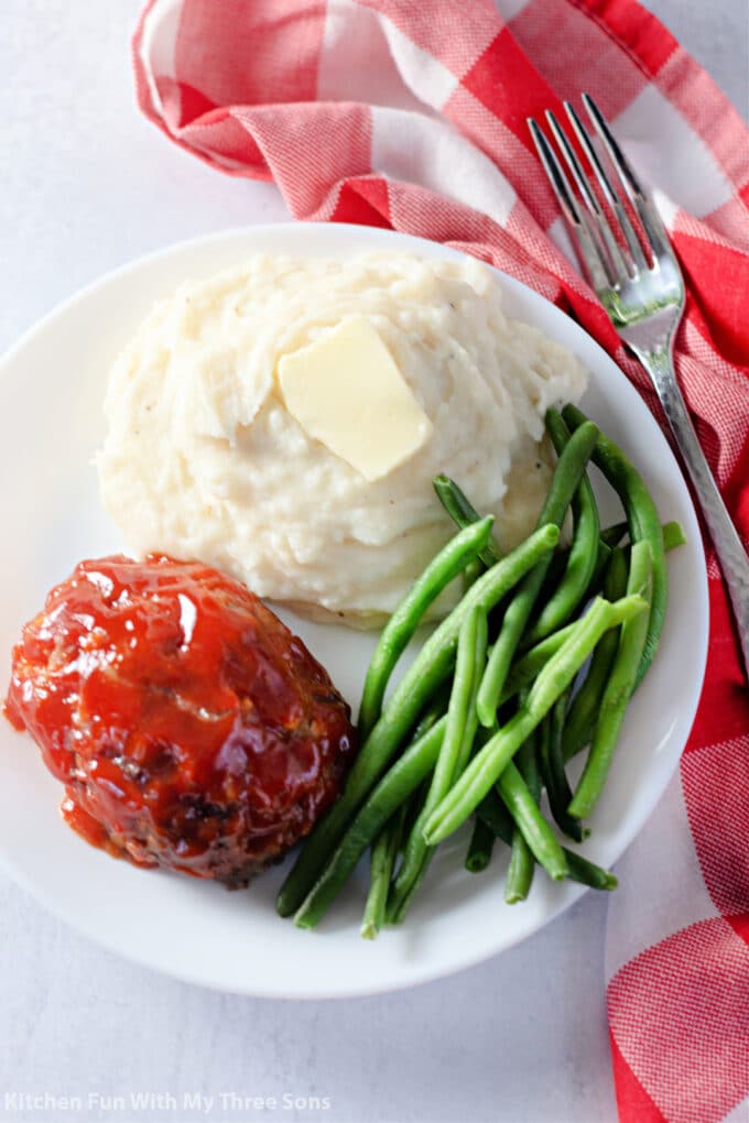 a white plate filled with mashed potatoes, green beans, and meatloaf.