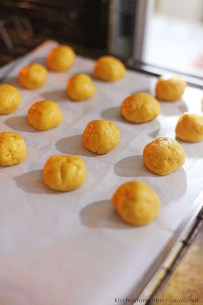 Cookie dough balls spread out on a baking sheet.