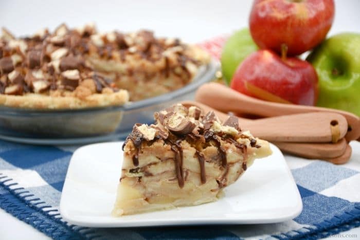 A slice of pie with a plate of apples on the side.
