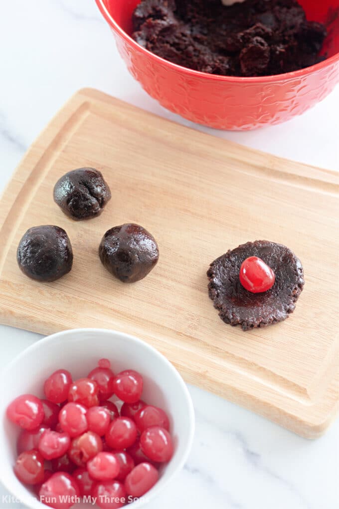 rolling chocolate batter around maraschino cherries.