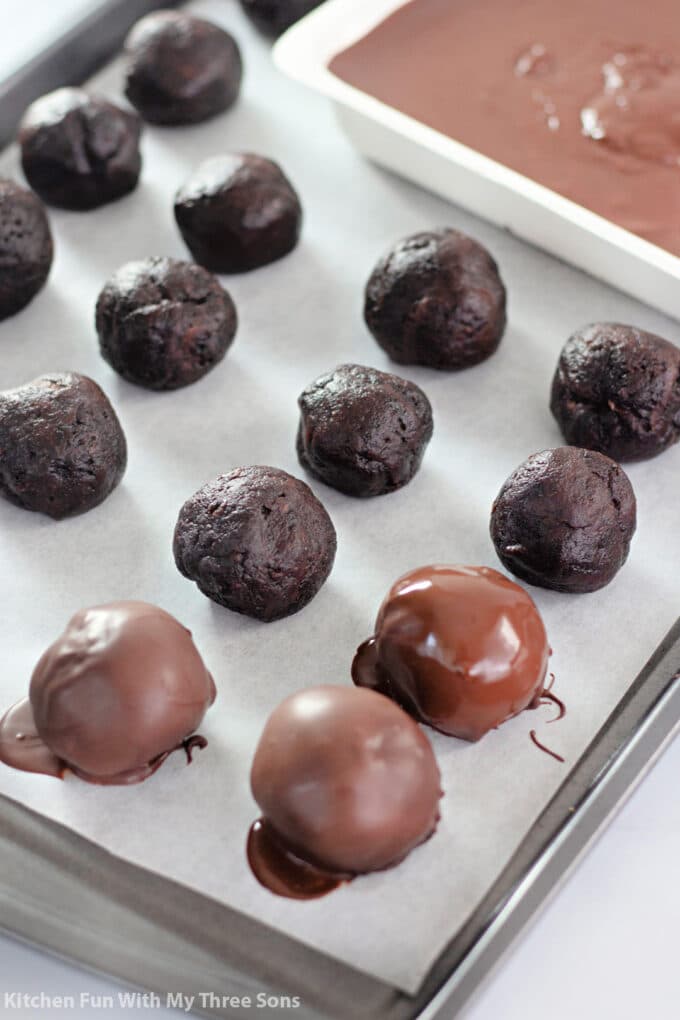 dipping brownie covered cherries in melted chocolate.