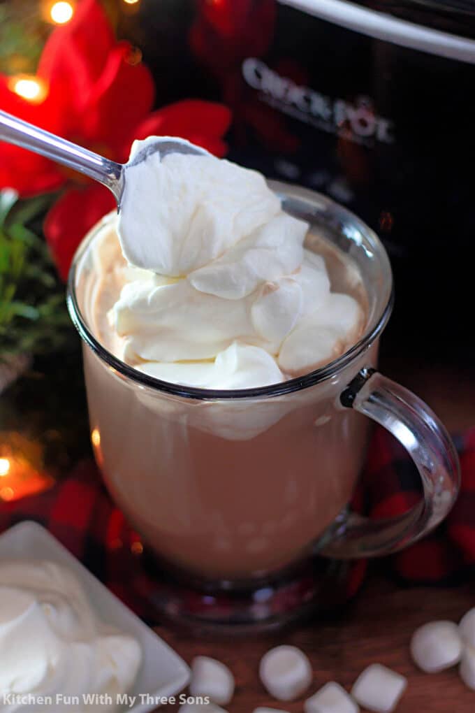 adding whipped cream to the hot cocoa.