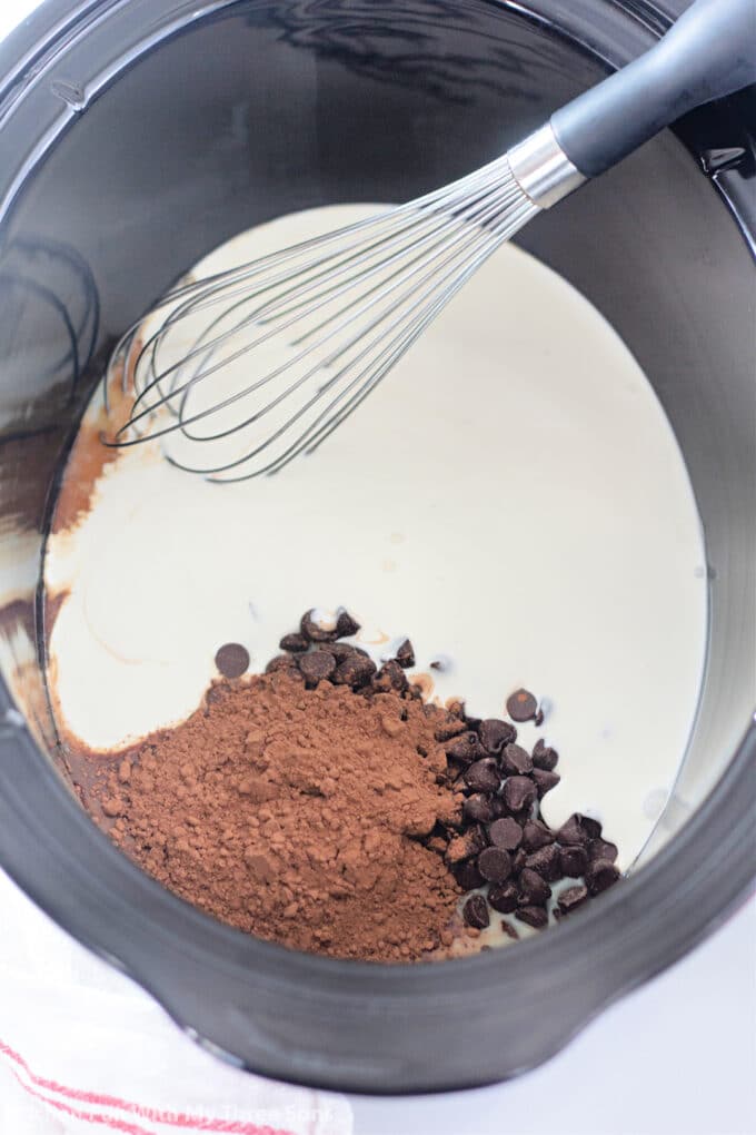 cream, milk, cocoa, and chocolate chips in a slow cooker with a whisk.