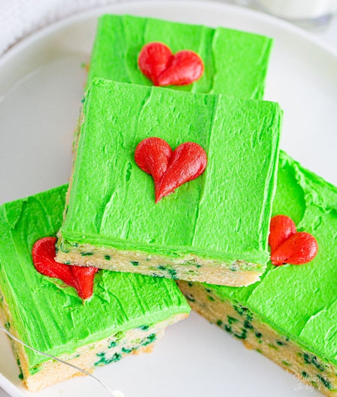 Grinch Bars are homemade sugar cookie bars with green sprinkles inside, topped with green frosting and a heart that's two sizes too small. Great Christmas dessert recipe.