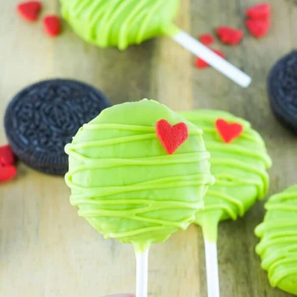 A hand holding up a grinch pop.