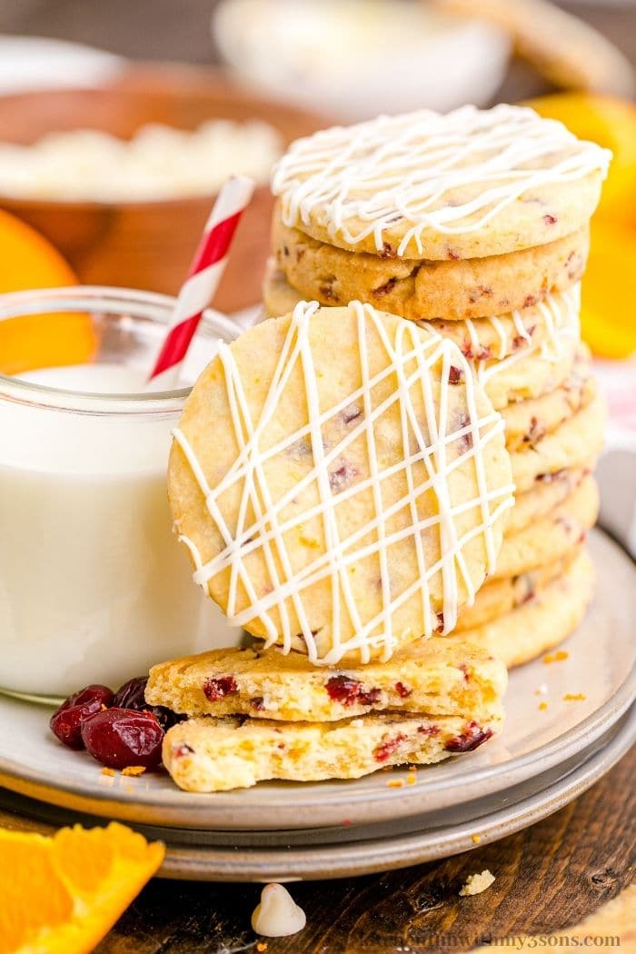 A orange cranberry cookie leaning against a stack of cookies.