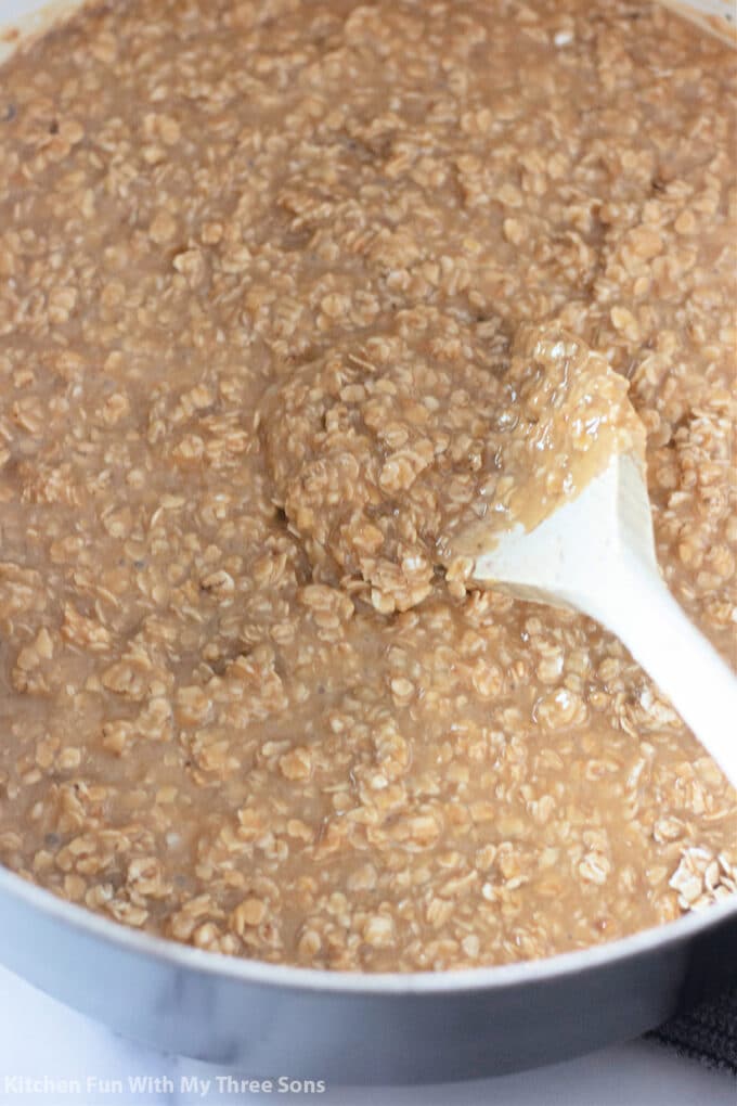 oats, milk, sugar, pb, vanilla, and butter in a pot with a wooden spoon.