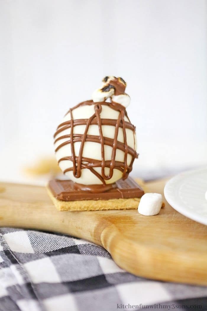 S'mores Hot Chocolate Bomb on a wooden paddle.