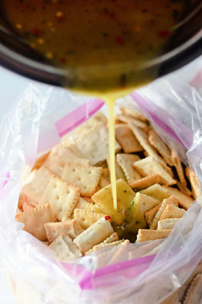 pouring seasoned oil over mini saltine crackers in a zip top bag.