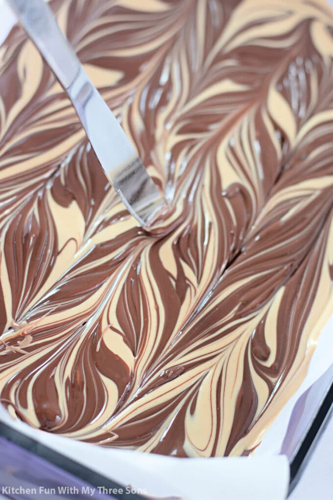 swirling the chocolate and peanut butter fudge together with a knife.