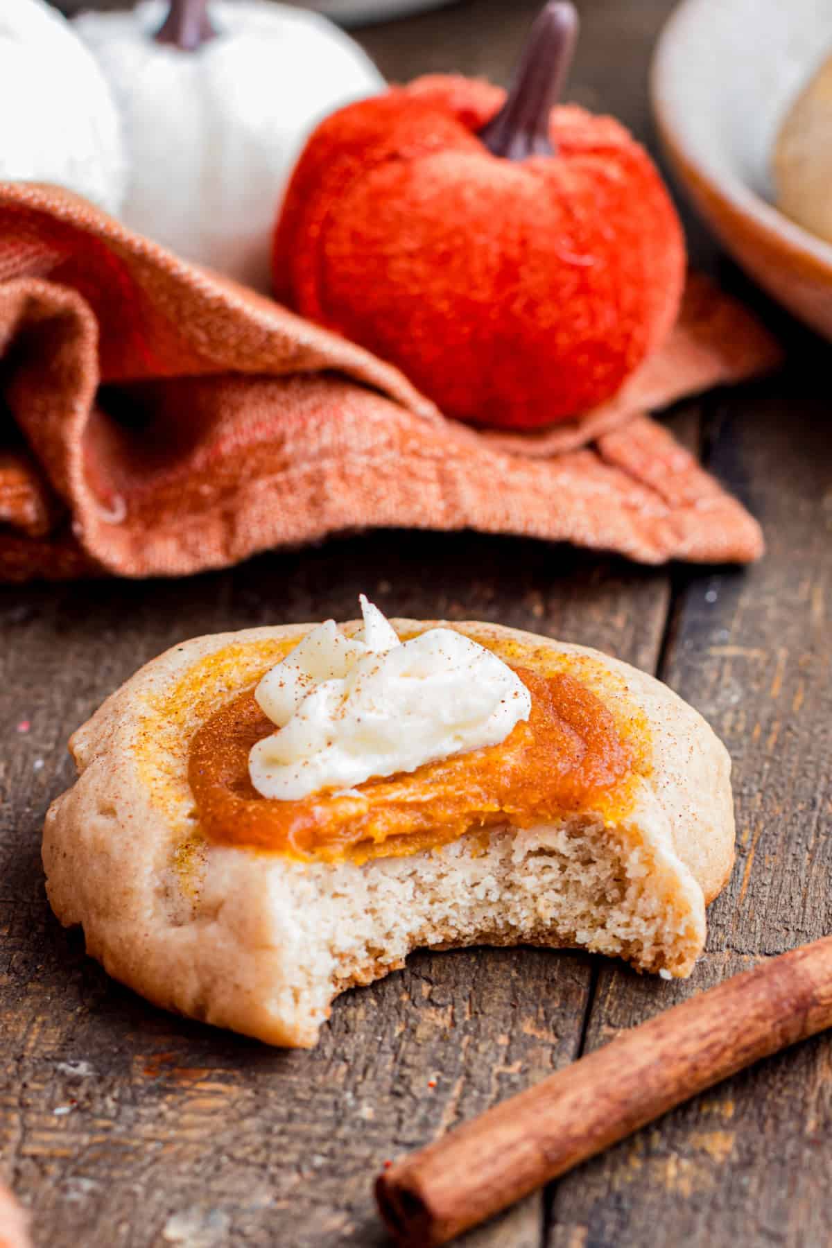 These Pumpkin Pie Cookies combine a soft, buttery cinnamon cookie with a creamy pumpkin pie filling baked right into the center. a bite taken out of a pumpkin pie cookie showing the inside.
