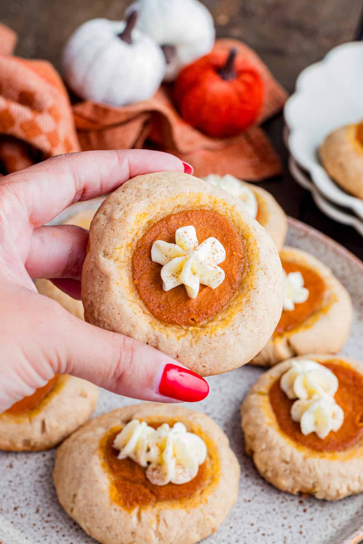 These Pumpkin Pie Cookies combine a soft, buttery cinnamon cookie with a creamy pumpkin pie filling baked right into the center. Hand holding a pumpkin pie cookie.