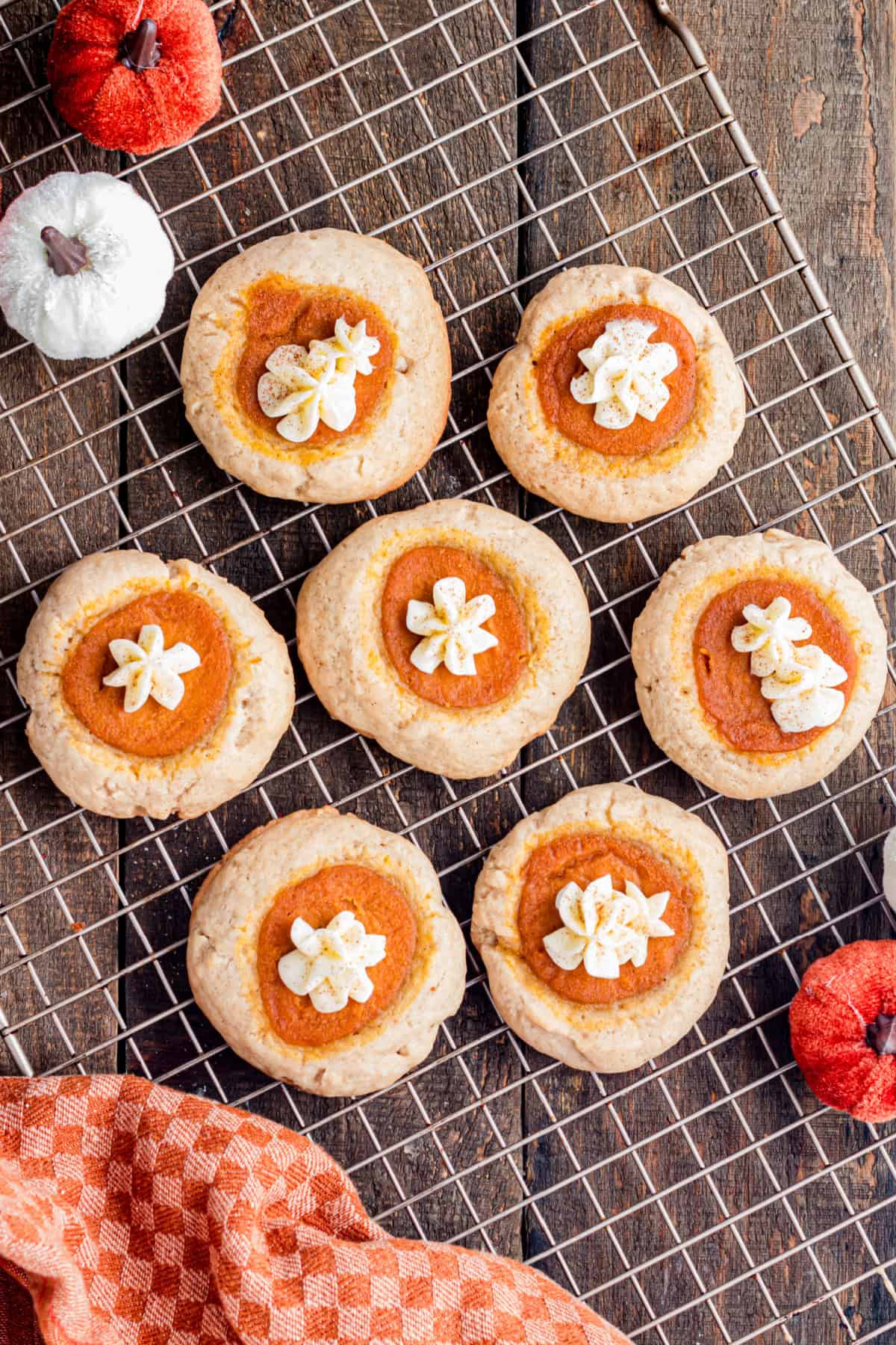 These Pumpkin Pie Cookies combine a soft, buttery cinnamon cookie with a creamy pumpkin pie filling baked right into the center. pumpkin pie cookies cooling on a rack