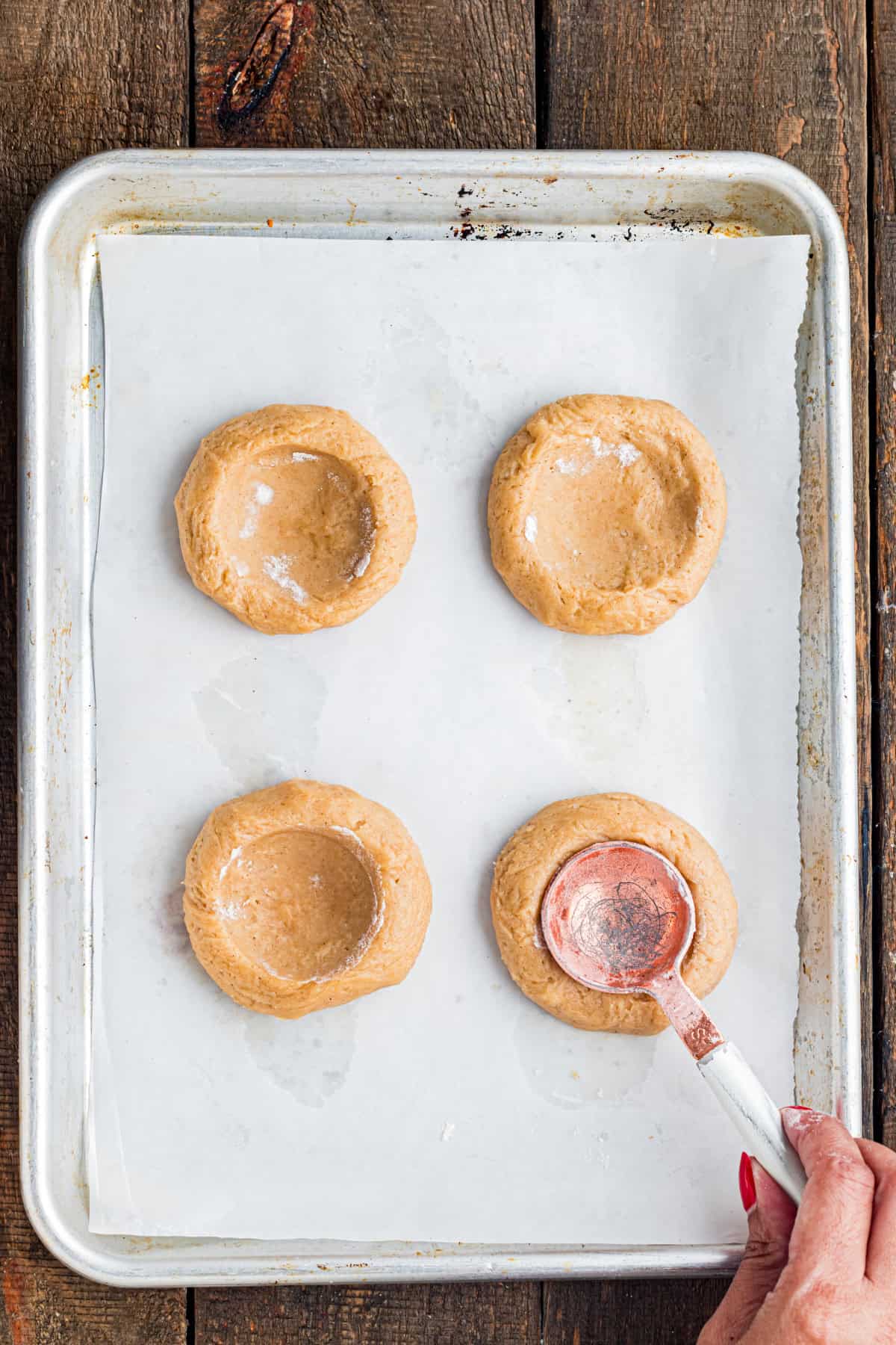 These Pumpkin Pie Cookies combine a soft, buttery cinnamon cookie with a creamy pumpkin pie filling baked right into the center. pressing a spoon into cookie dough on a baking sheet