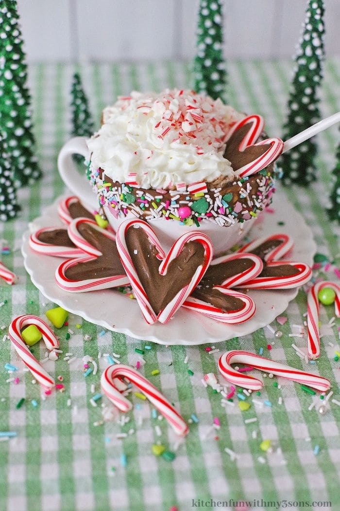 A cup full of cocoa with candy hearts with chocolate.