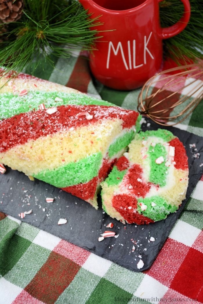 The candy cane cake roll on a colorful table cloth.