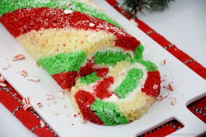 The candy cane rolled cake on a white cutting board.