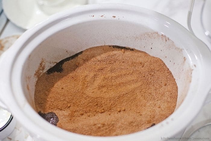 Adding the cocoa into the crockpot.
