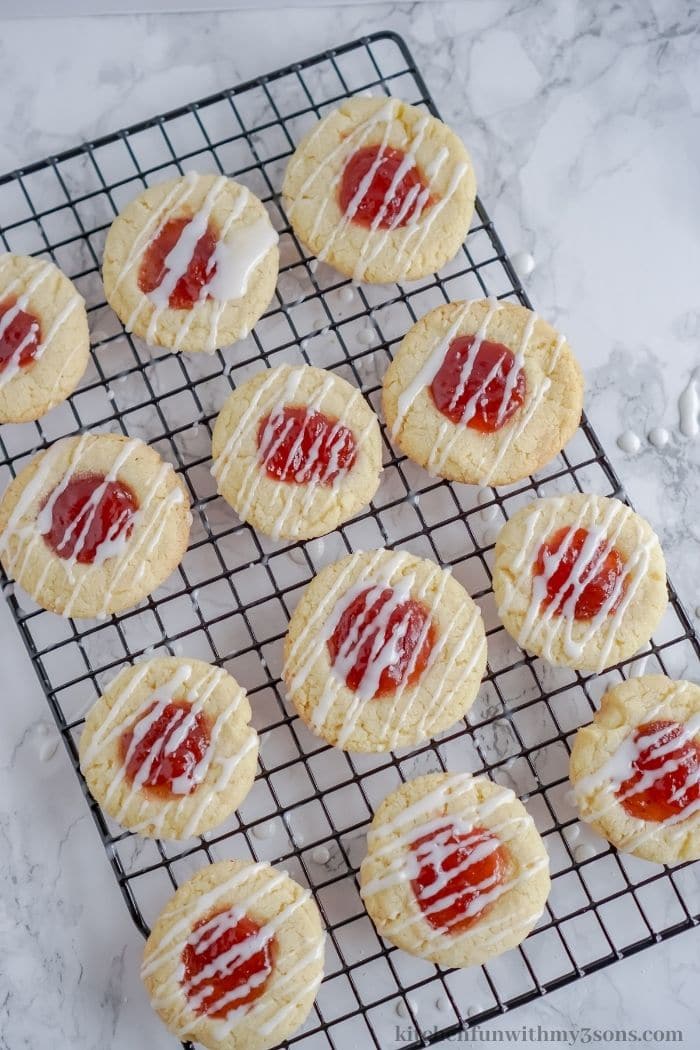 strawberry thumbprint cookies being drizzled with glaze.