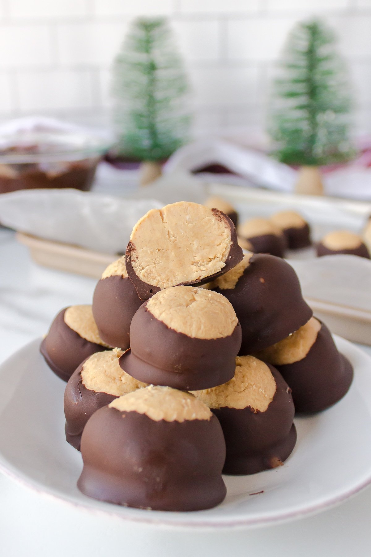 A neat stack of buckeye peanut butter balls, with the top buckeye cut in half to reveal the peanut butter center.