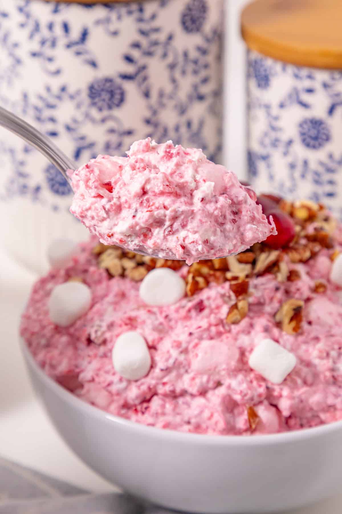 This Cranberry Fluff Salad is a blend of chopped cranberries, crushed pineapple and mini marshmallows tossed in a sweetened whipped cream cheese mixture. a big spoonful of cranberry fluff taken out of the serving bowl.