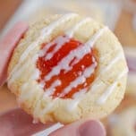 Close up of a hand holding up a strawberry thumbprint cookie.