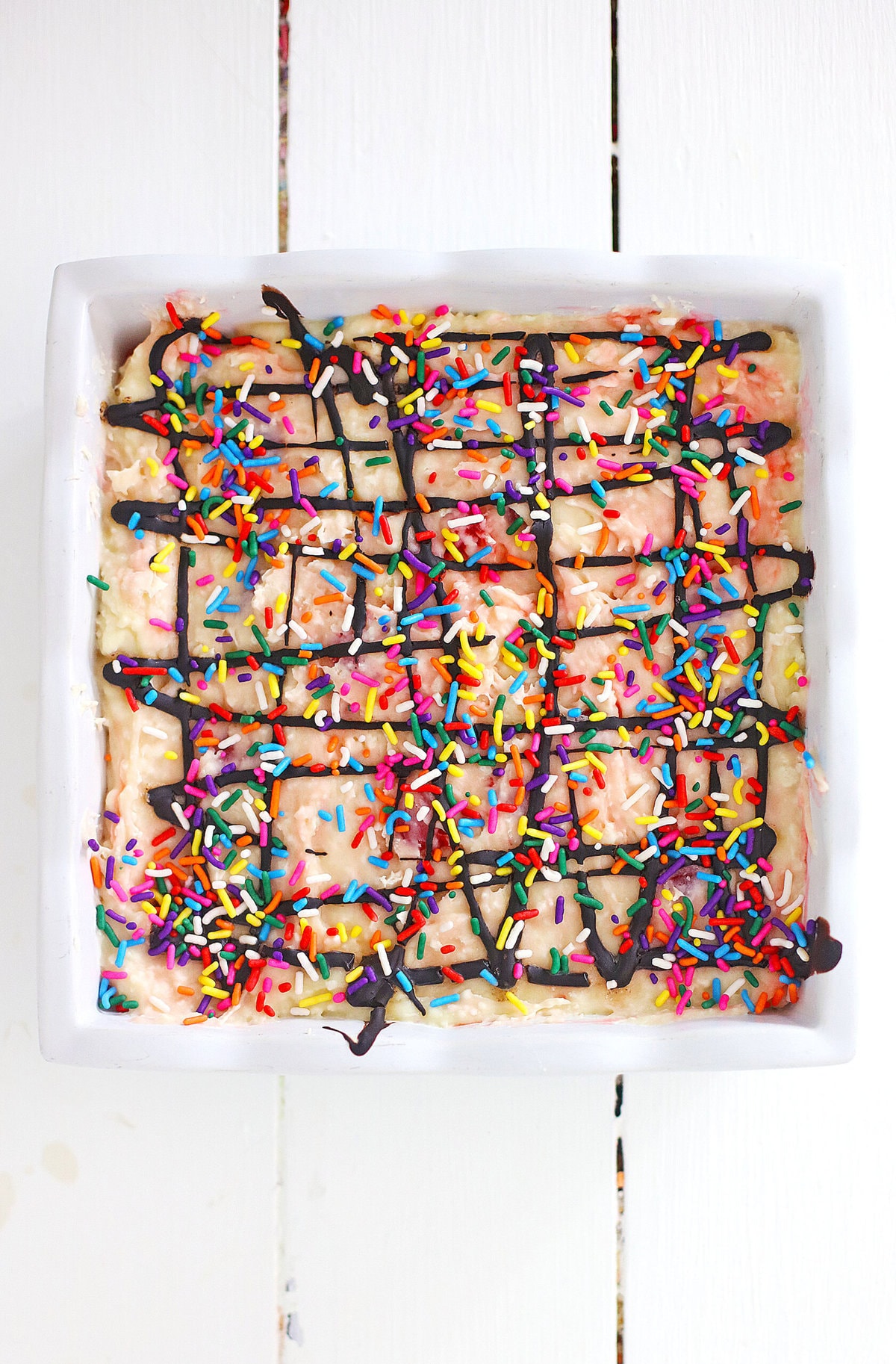 Banana fudge in a baking dish topped with sprinkles and hot fudge
