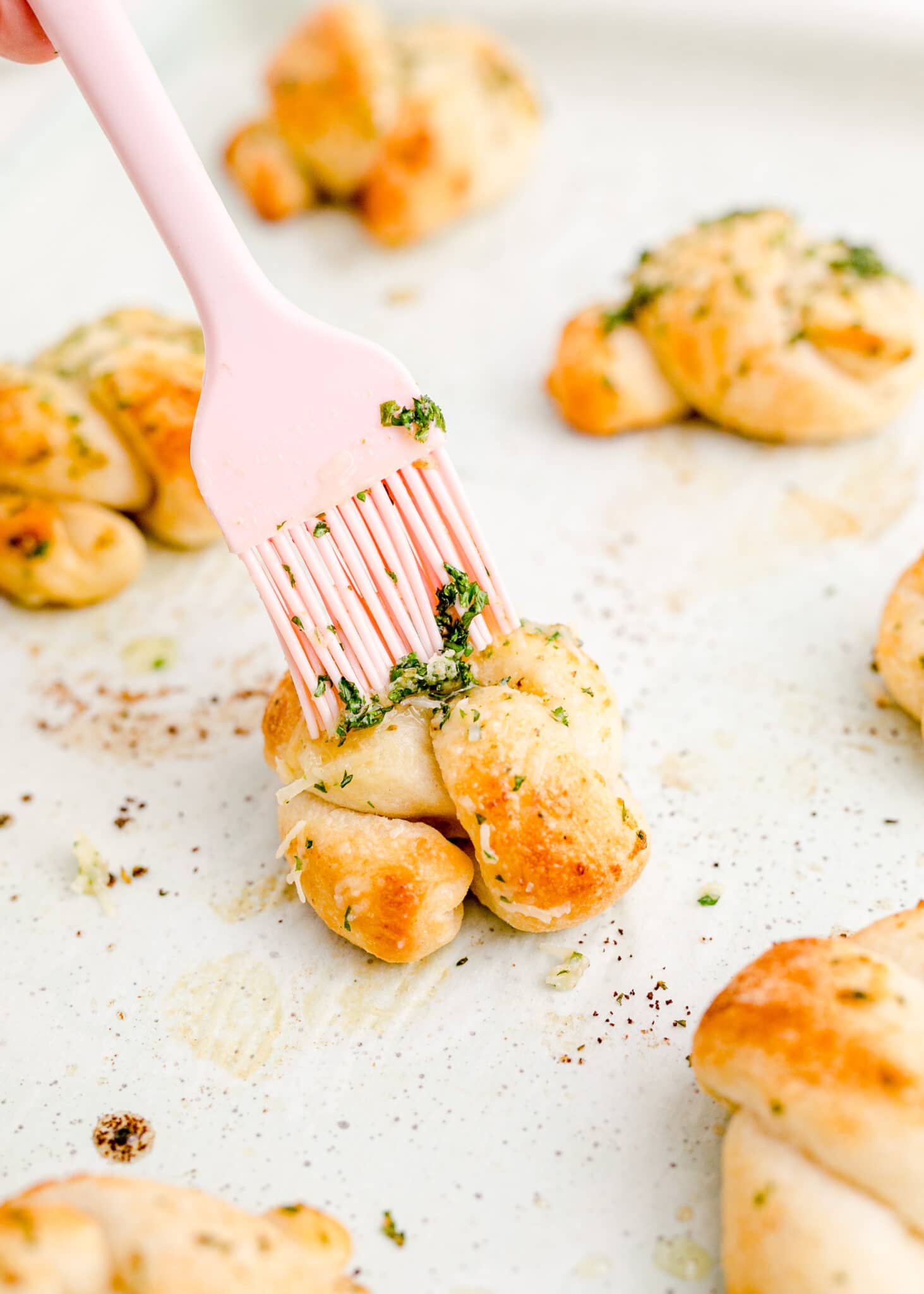 The tops of the pizza dough knots are brushed with garlic butter.