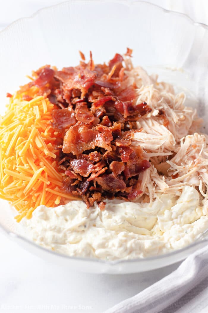 cream cheese, ranch dressing, chicken, bacon, and cheese in a mixing bowl.