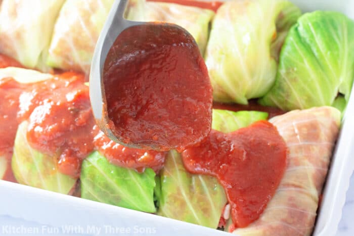 pouring homemade tomato sauce over cabbage rolls.
