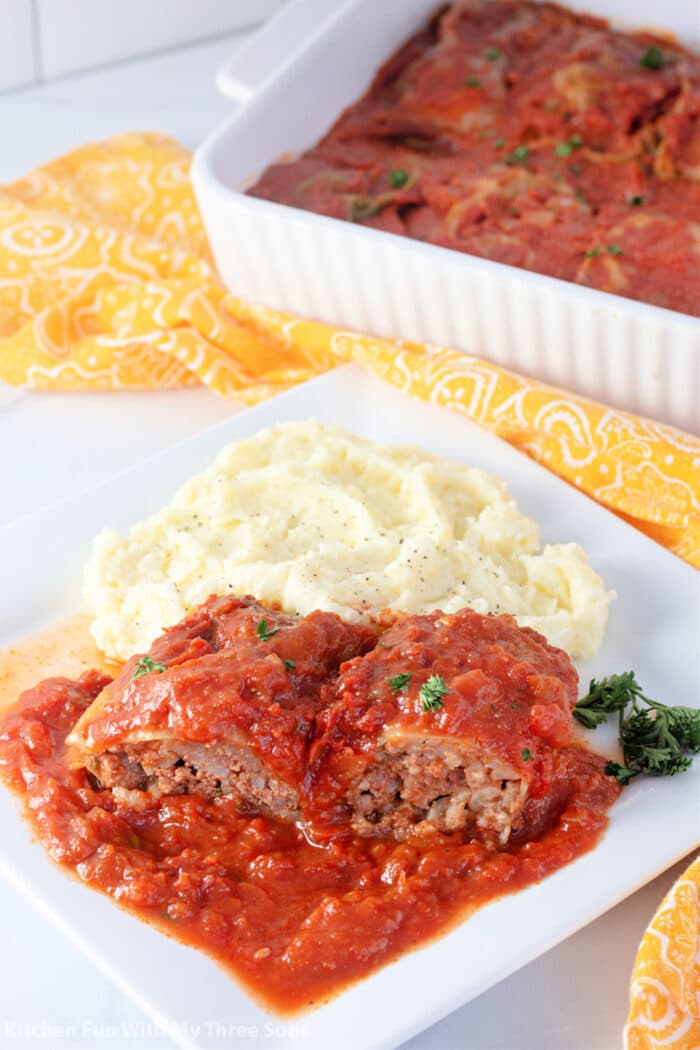 Stuffed Cabbage Rolls with mashed potatoes on a white plate.