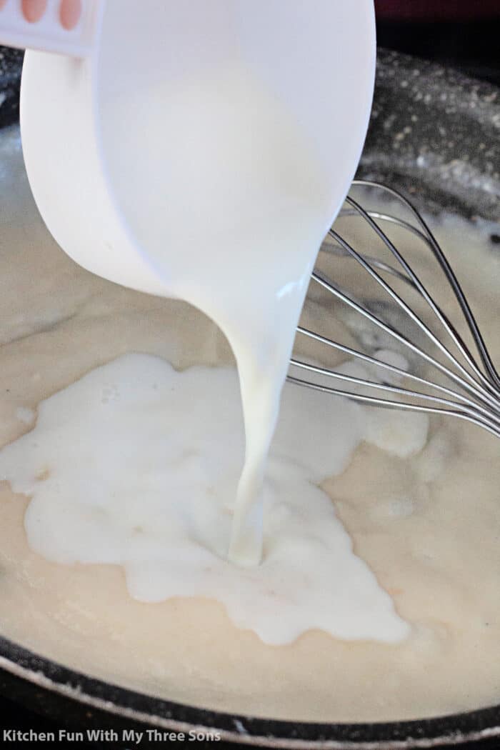 pouring milk into the cheese sauce.