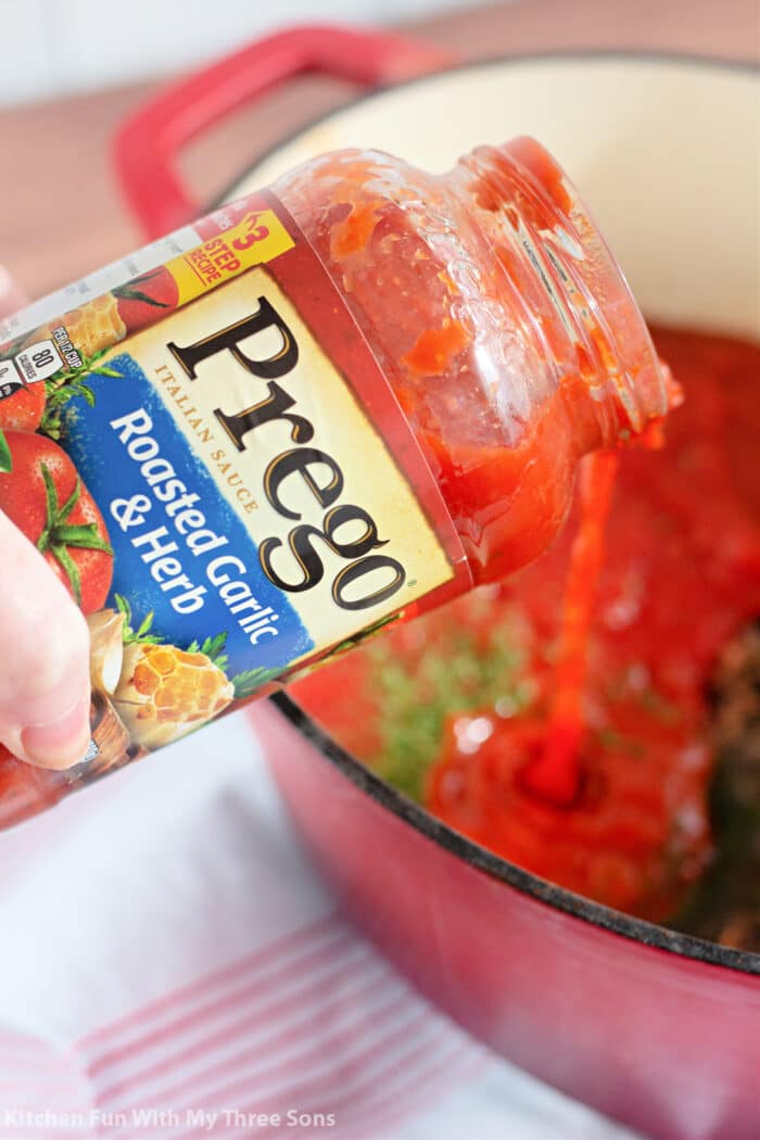 Pouring Prego pasta sauce into the lasagna soup.
