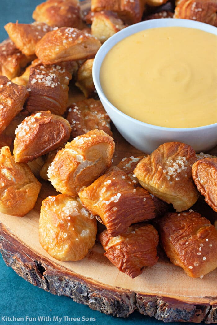 Soft Pretzel Bites with cheese sauce on a wooden tray.