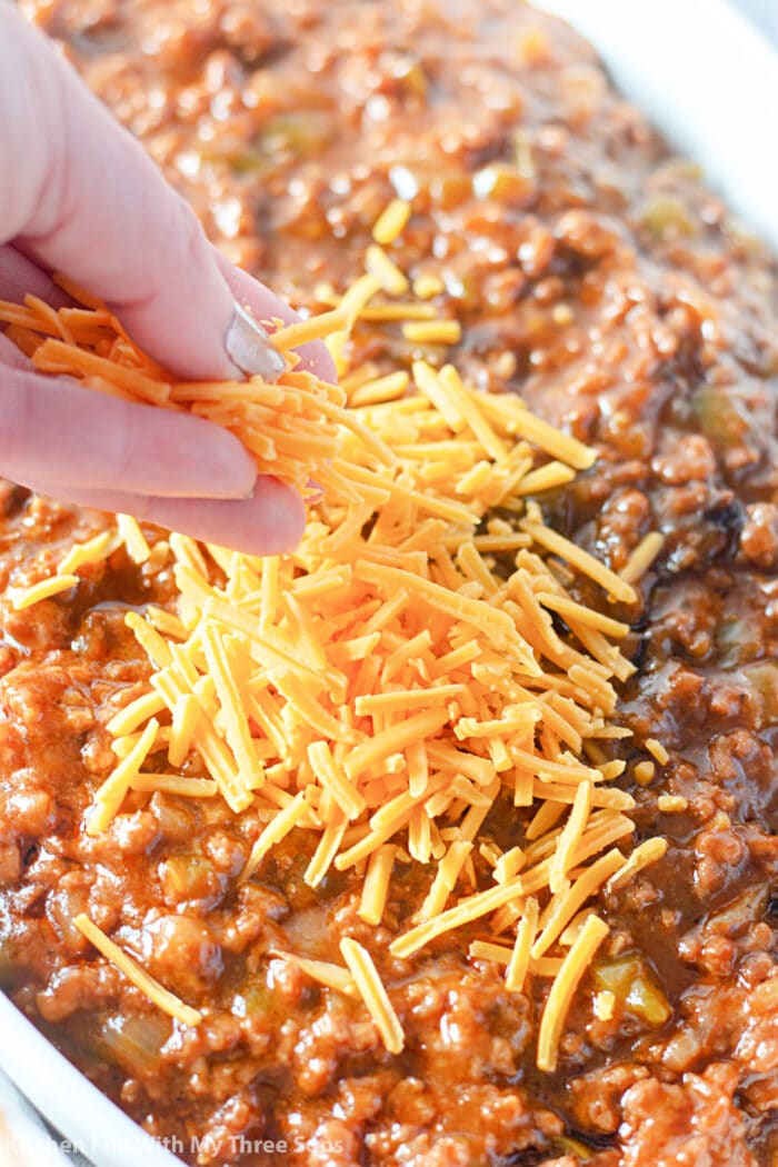 Sprinkling shredded cheddar cheese over the dip.