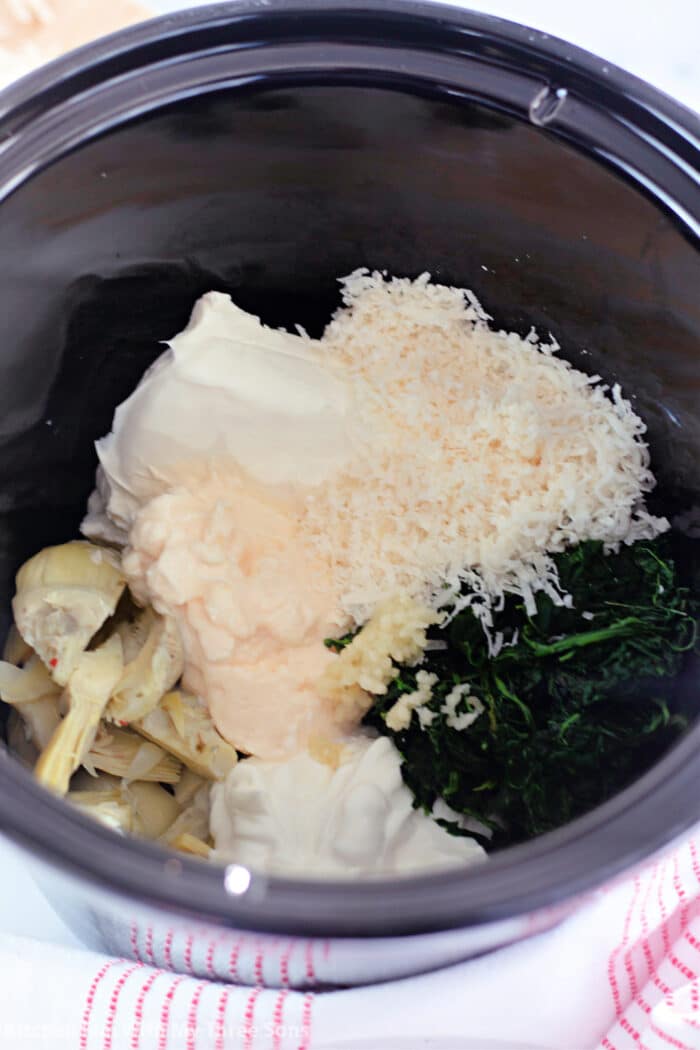 cream cheese, parmesan cheese, artichokes, spinach, garlic, sour cream, and mayonnaise in a slow cooker.