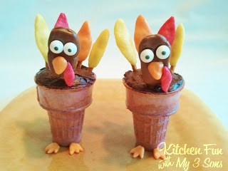 Two Thanksgiving turkey cupcake cones on top of a dessert stand