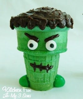 A Frankenstein ice cream cone that has been dyed green and decorated with black icing