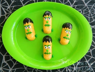 Four Twinkies on a party platter with frosting decorating them to look like Frankenstein's monster