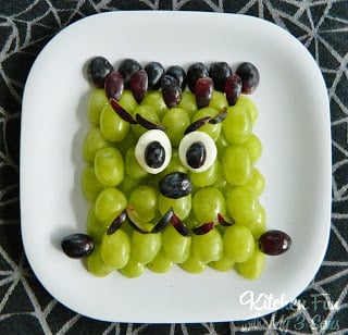 A plate of grapes with a Frankenstein face made out of food