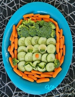 A plate of healthy party food with chopped veggies arranged to look like a Halloween face
