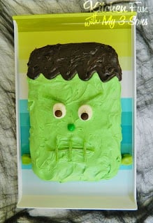 A Frankenstein-themed Halloween cake on a party platter on top of a kitchen countertop