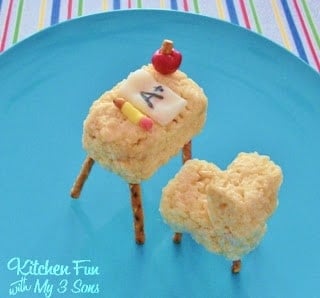 Two Rice Krispie Treats decorated to look like a desk and chair with pretzel sticks as the legs