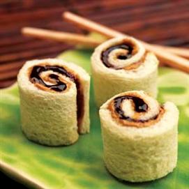 Peanut butter and jelly "sushi rolls" on top of a plate beside a pair of chopsticks