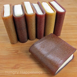 Seven little schoolbook snacks made out of fruit leathers on top of a wooden surface