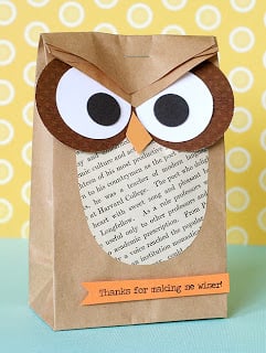A paper school lunch bag decorated to look like an owl with snacks for a teacher inside